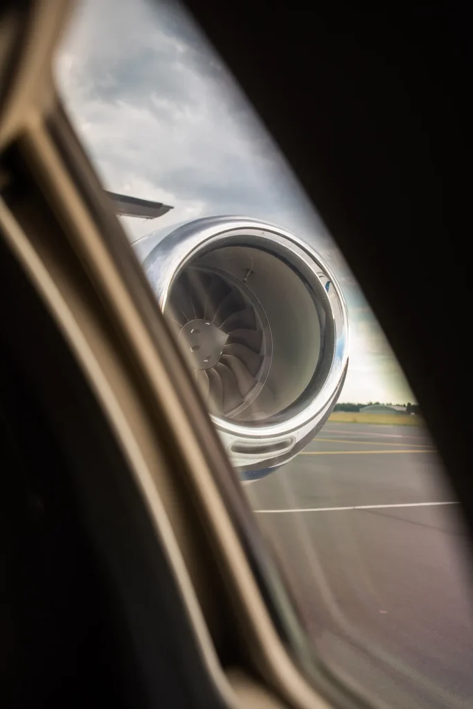 View through an airplane window focusing on a polished jet engine, symbolizing readiness and high performance. Ideal for illustrating jet card membership benefits like guaranteed availability, efficiency, and elite travel convenience.